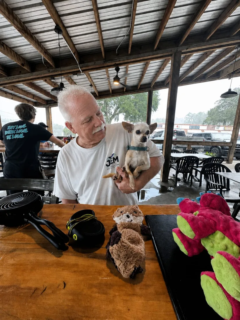 Jimmy Maige, general contractor and owner of JEM Construction of Tallahassee, holding his dog at a table